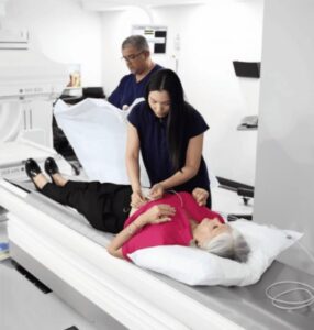 Personal preparando a una paciente sobre la mesa de la cámara gamma para un estudio de medicina nuclear